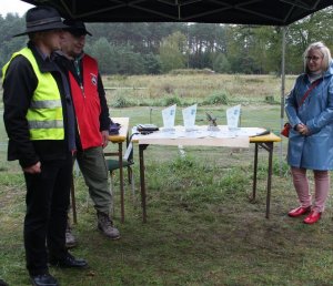 Na zdjęciu Joanna Napiwodzka Wicestarosta Policki, Prezes Stowarzyszenia Grajcar oraz sędzia zawodów strzeleckich, a w tle na stole statuetki i dyplomy przygotowane dla uczestników