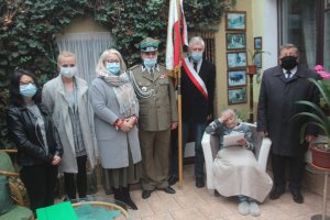 Zdjęcie przedstawia Krystynę Łanowską oraz stojących obok niej po lewej stronie Burmistrza Polic, po prawej stronie Wicestarostę Polickiego oraz przedstawicieli Związku Kombatantów Rzeczypospolitej Polskiej i Byłych Więźniów Politycznych