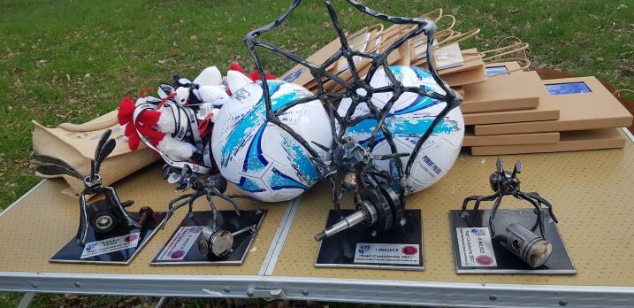 Statuetki oraz nagrody przygotowane dla uczestników na stoliku na świeżym powietrzu