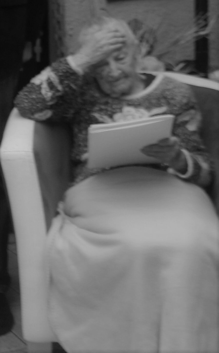 Krystyna Łanowska siedząca w fotelu, okryta kocem i podpierająca głowę prawą ręką