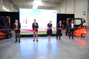 Zaproszeni goście przecinają wstęgę podczas otwarcia fabryki wózków przemysłowych