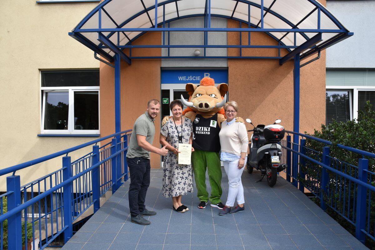 Organizator Dzikiego Weekendu Wojciech Bobrowski wraz z przedstawicielami Powiatu Polickiego: Wicestarostą Polickim Joanną Napiwodzką i Członkiem Zarządu Powiatu w Policach Beatą Chmielewską pozujący do zdjęcia z maskotką wydarzenia - "Pluszowym Dzikiem"