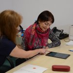 Senior z Powiatu Polickiego przy biurku wraz ze specjalistą rozwiązuje testy na tablecie