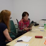 Senior z Powiatu Polickiego przy biurku wraz ze specjalistą rozwiązuje testy na tablecie