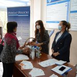 2 osoby stojące przy biurku przekazują upominek seniorowi