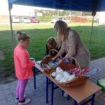 Uczennica po badaniu w Dentobusie odbiera upominku z namiotu promocyjnego