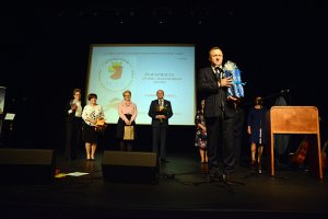 Starosta Policki Andrzej Bednarek przemawia na scenie, a w tle stoją Przewodniczący Rady Powiatu w Policach Cezary Arciszewski, Wicestarosta Policki Joanna Napiwodzka oraz inni goście