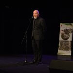 Ksiądz kanonik przemawia na scenie