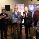 Moment gratulacji i podziękowań dla autora książki. Od lewej Przewodniczący Rady Powiatu w Policach Cezary Arciszewski, Burmistrz Polic Władysław Diakun, autor książki Stefan Marszałek, Starosta Policki Andrzej Bednarek, syn wraz z wnuczkiem autora książki. W tle niebieski baner z napisem Powiat Policki.