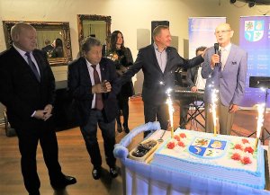 Moment złożenia życzeń z okazji urodzin dla autora książki. Od lewej Przewodniczący Rady Powiatu w Policach Cezary Arciszewski, Burmistrz Polic Władysław Diakun, Starosta Policki Andrzej Bednarek oraz autor książki Stefan Marszałek. Okolicznościowy tort z racami, a w tle niebieski baner z napisem Powiat Policki.