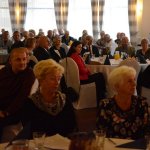 Zbliżenie gości, siedzących przy okrągłych stołach i słuchających wystąpień.