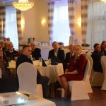 Zbliżenie gości, siedzących przy okrągłych stołach i słuchających wystąpień.