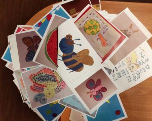 Na stole biurkowym rozłożone prace plastyczne dzieci biorących udział w konkurskie pn Zaprojektuj odblask