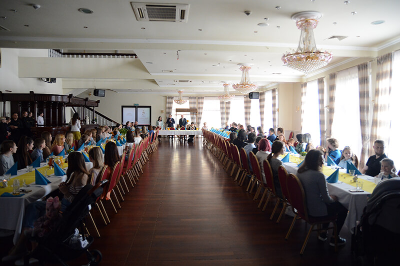 Uczestnicy spotkania świątecznego przy wspólnym stole w sali balowej