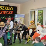 aktorzy przedstawiający scenę wyrywania wielkiej rzepy wspólnymi siłami, w tle napis świeto szkoły i dzień dziecka.