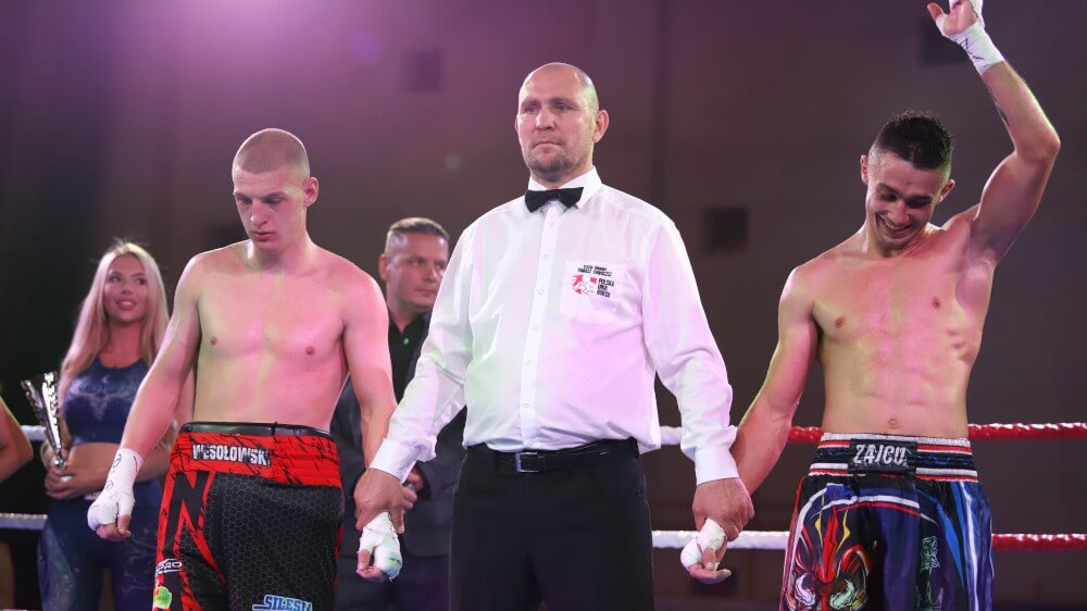 Sędzia i dwóch zawodników w ringu bokserskim