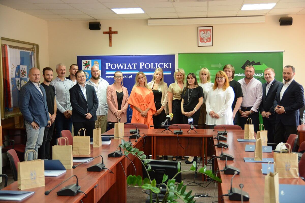 Zdjęcie grupowe osób, które skorzystały z dotacji PUP w sali sesyjnej