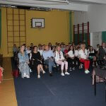 zaproszeni goście wraz z młodzieżą siedzący w halce sportowej na rozpoczęciu wydarzenia