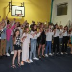 Młodzież z kolonii trzymająca się za ręce śpiewa piosenki