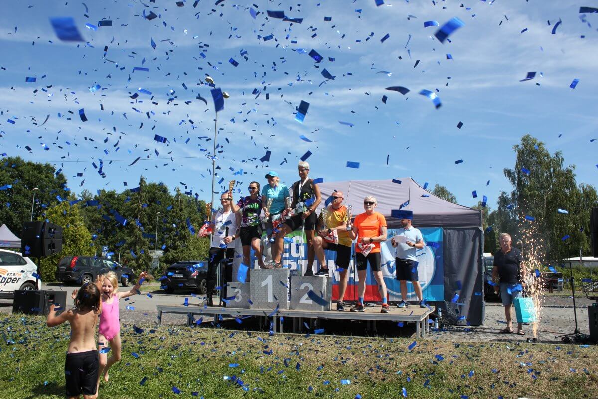 zwycięzcy biegu - seniorzy na podium, wokoł przemieszcza się konfetti