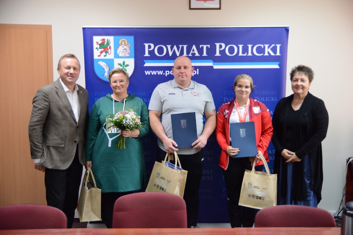 Starosta Policki Andrzej Bednarek, Członek Zarządu Powiatu w Policach Beata Chmielewska oraz Oliwia Styczyszyn z rodzicem i trenerem na wspólnym zdjęciu