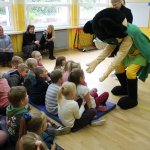 Maskotka przybija piątki z dziećmi siedzącymi w sali gimnastycznej