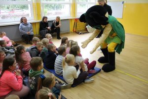 Maskotka przybija piątki z dziećmi siedzącymi w sali gimnastycznej