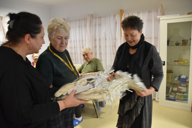 Trzy stojące kobiete, trzymające w dłoniach anioły zapakowane w celofan