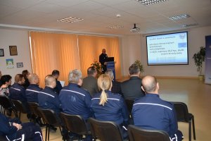 Siedząca na krzesłach grupa policjantów na sali konferencyjnej podczas odprawy.