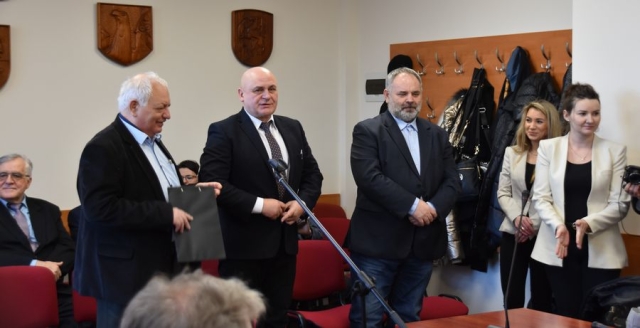 Obrady sesji Rady Powiatu w Policach, w części przeznaczonej dla widowni witani goście stoją przy krzesłach