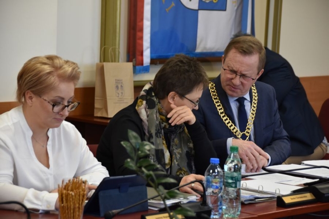 Podczas obrad sesji Rady Powiatu w Policach przy stole na krzesłach siedzi Zarząd Powiatu w Policach, czyli dwie kobiety i jeden męźczyzna