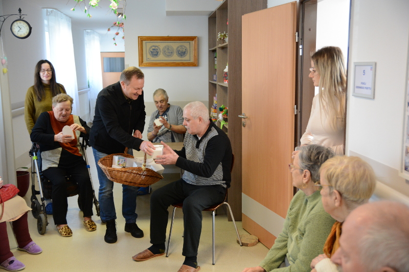 Starosta Policki Andrzej Bednarek wręcza siedzącym osobom upominek