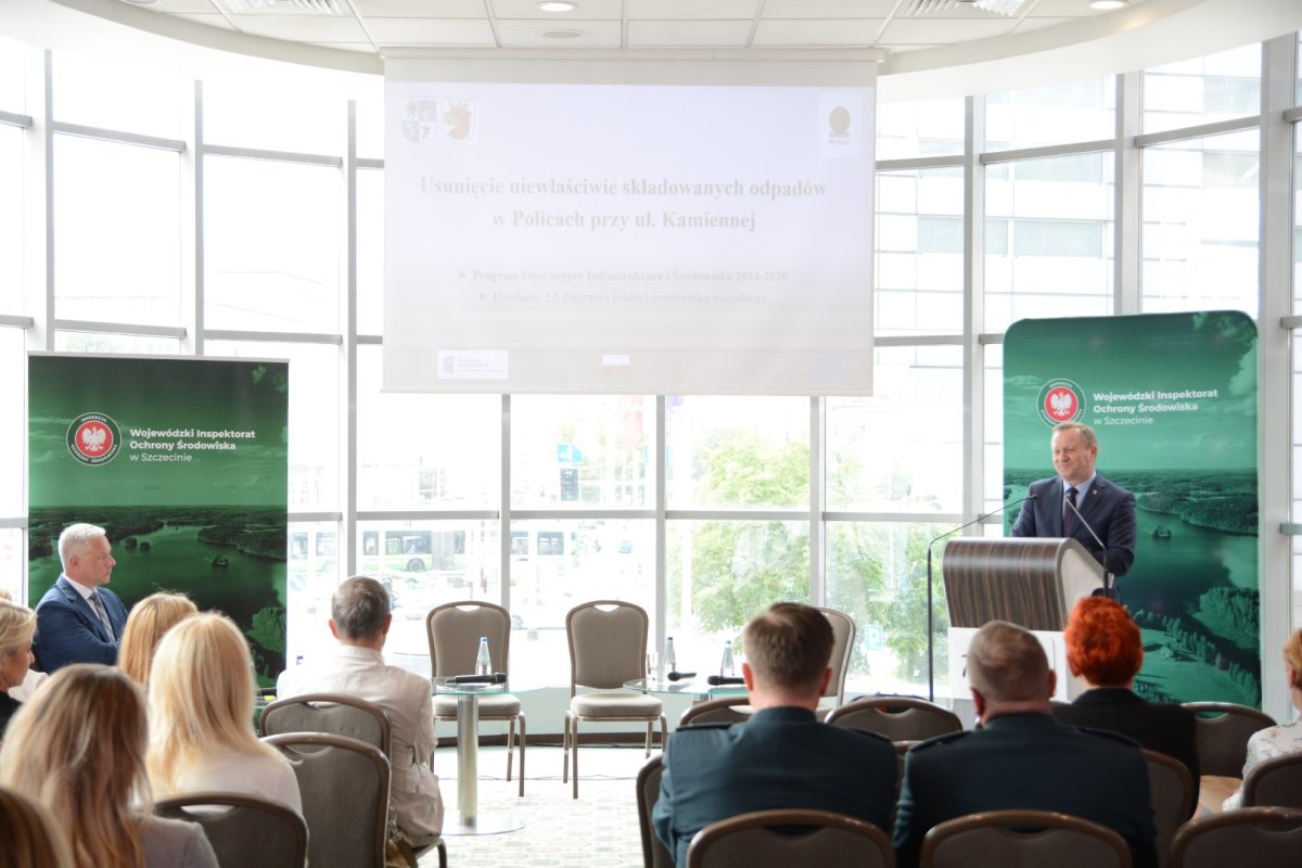 Po prawej stronie przy mównicy Starosta Policki Andrzej Bedanrek, po lewej moderator spotkania, a po środku rzutnik