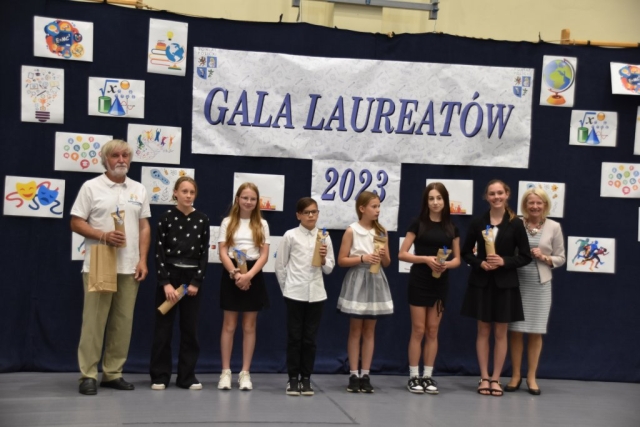 Opiekun oraz nagrodzeni uczniowie pozują do zdjęcia grupowego.