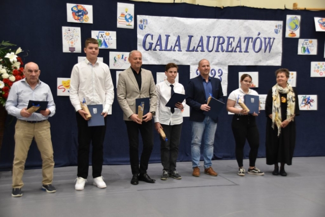 Laureaci pozujący do zdjęcia grupowego z dyplomami i upominkami.