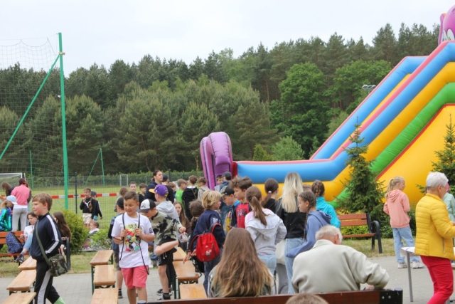 Tłum dzieci bawiących się na placu szkolnym pod czas Dnia Dziecka.