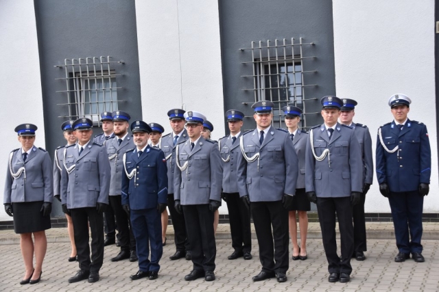 Kilkudziesięcioosobowa grupa umundurowanych policajntów, składająca się z kobiet i mężczyzn na dziedzińcu komendy podczas apelu.