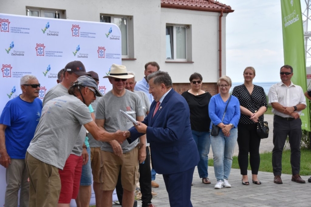 Władysław Diakun Burmistrz Polic wręczający dyplom dla uczestników 59. Etapowych Regat Turystycznych, w tle Joanna Napiwodzka Wicestarosta Policki oraz Małgorzata Siemianowska Radna Powiatu Polickiego.
