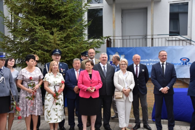 Kilkunastoosobowa grupa składająca się z mężczyzn i kobiet, uczestników apelu z okazji Świeta Policji pozujący do zdjęcia grupowego na dziedzińcu Komendy Powiatowej Policji w Policach.