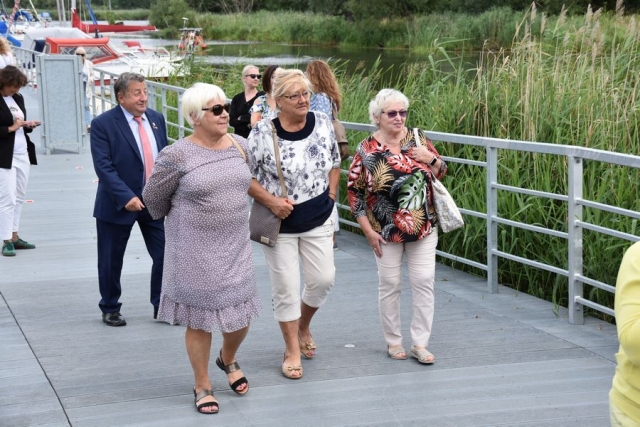 Zaproszeni goście, spacerujący po pomoście wzdłuż rzeki Łarpia