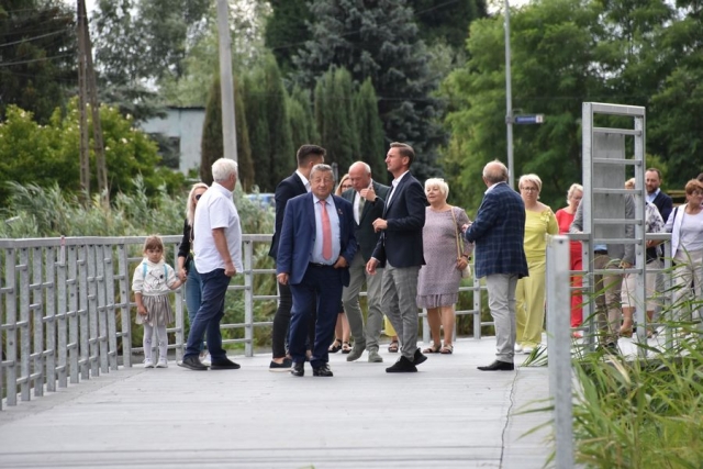 Zaproszeni goście, spacerujący po pomoście wzdłuż rzeki Łarpia
