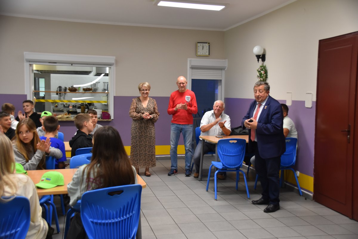 Burmistrz Polic przemawiajacy do kolonii na stołówce w celu powitania nowych gości, na zdjęciu widoczna jest Wicestarosta Joanna Napiwodzka oraz opiekun grupy z SOSW nr 1.
