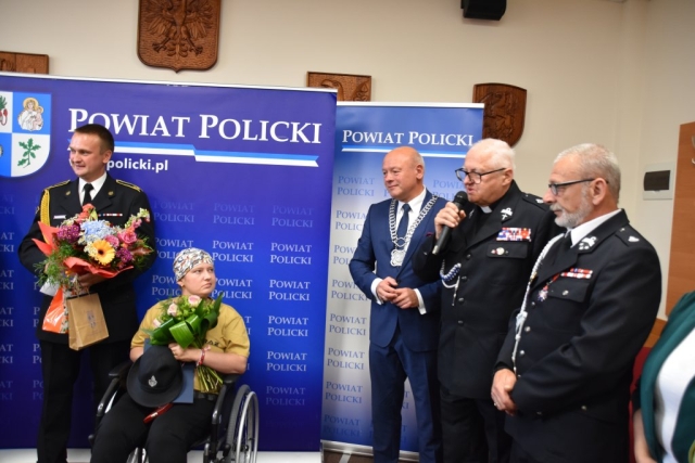 zgromadzenie ludzi, przemowa do p. Mariki na tle ścianki Powiatu Polickiego