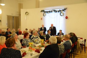 W tle dwóch mężczyzn stojących, z przodu siedzący ludzie