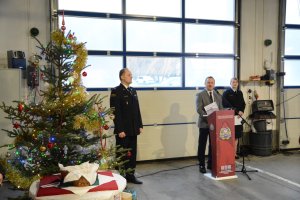 Starosta Policki przy mównicy, obok komendant straży i choinka