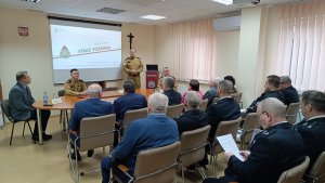 Siedzące osoby na pierwszym planie, w tle projektor i stojące osoby