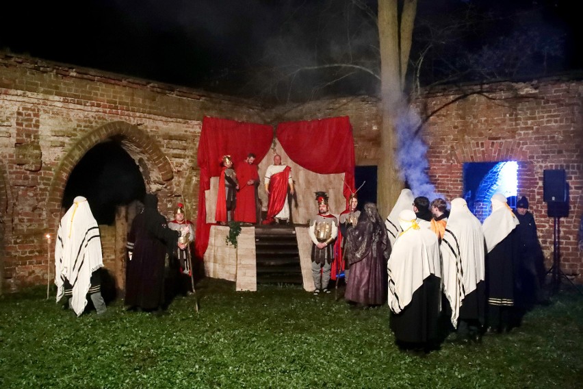 W tle scena, stojące osoby w przebraniach