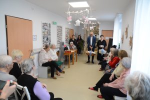 Siedzące wokół osoby, w tle stojące 4 osoby