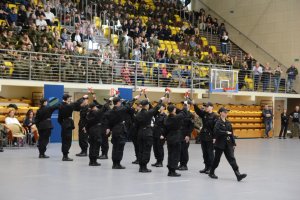 Stojące osoby, w tle na trybunach siedzące osoby