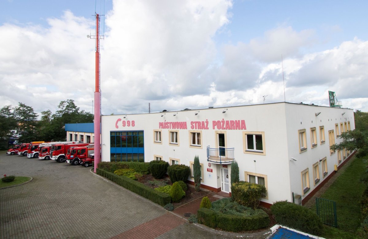 Budynek, w tle wozy strażackie
